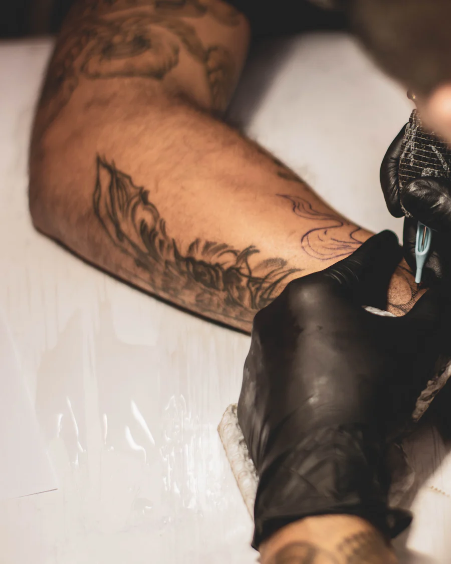 Tattoo artist in black gloves working with a machine on a client's forearm